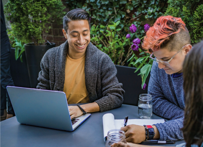 Three people around a table collaborating on work together positively.